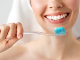 mujer sonriendo sosteniendo un cepillo de dientes con pasta de dientes Colgate.