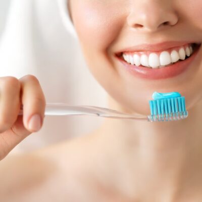 mujer sonriendo sosteniendo un cepillo de dientes con pasta de dientes Colgate.