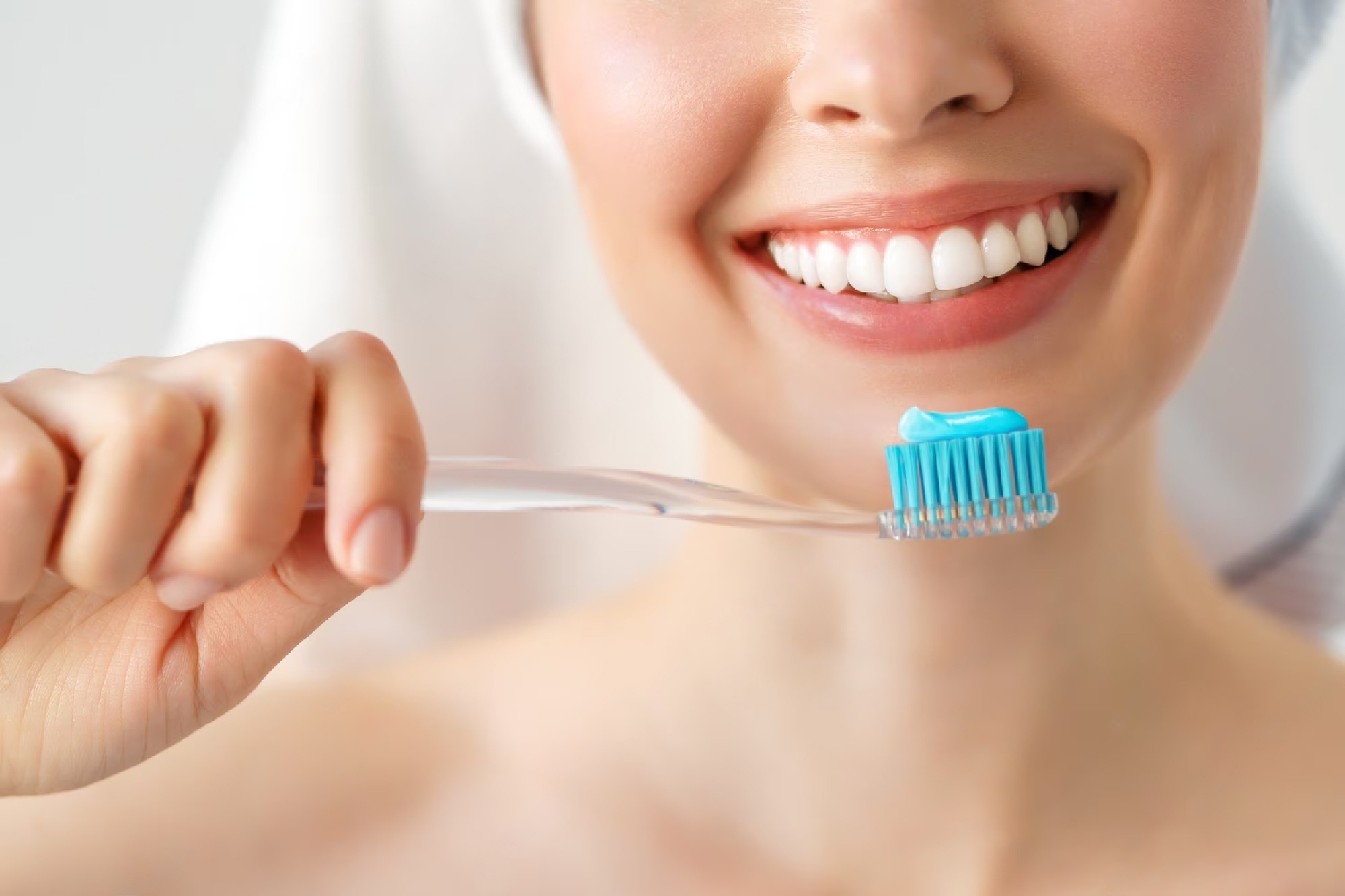 mulher sorrindo segurando escova de dentes com creme dental Colgate.